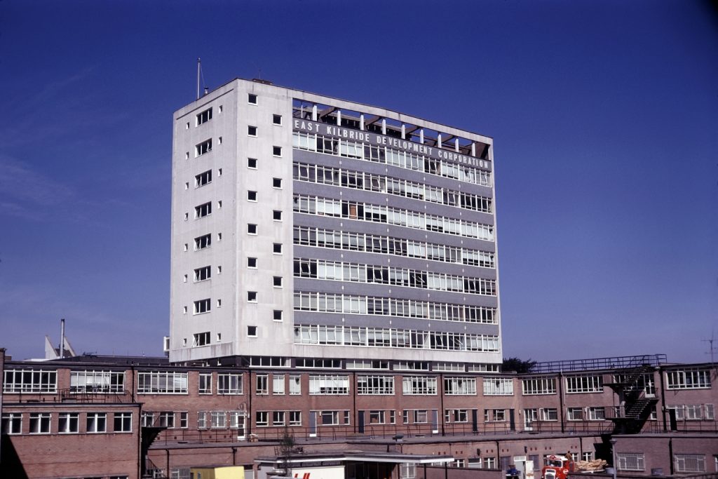 A large, concrete, grey, rectangle building sits newly built in the sun.